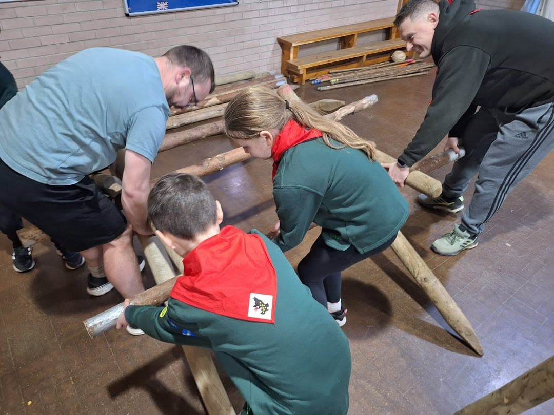 Cubs tying knots and lashing poles together for a pioneering project