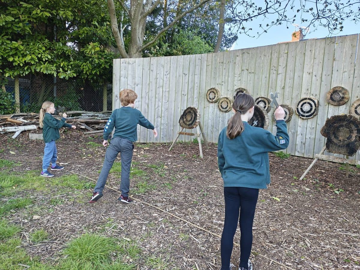 A Cub throwing an axe at a target during an outdoor session